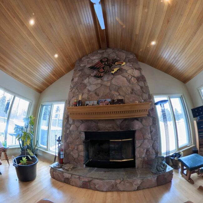 living room with fireplace that reaches the roof and wooden panels on the roof